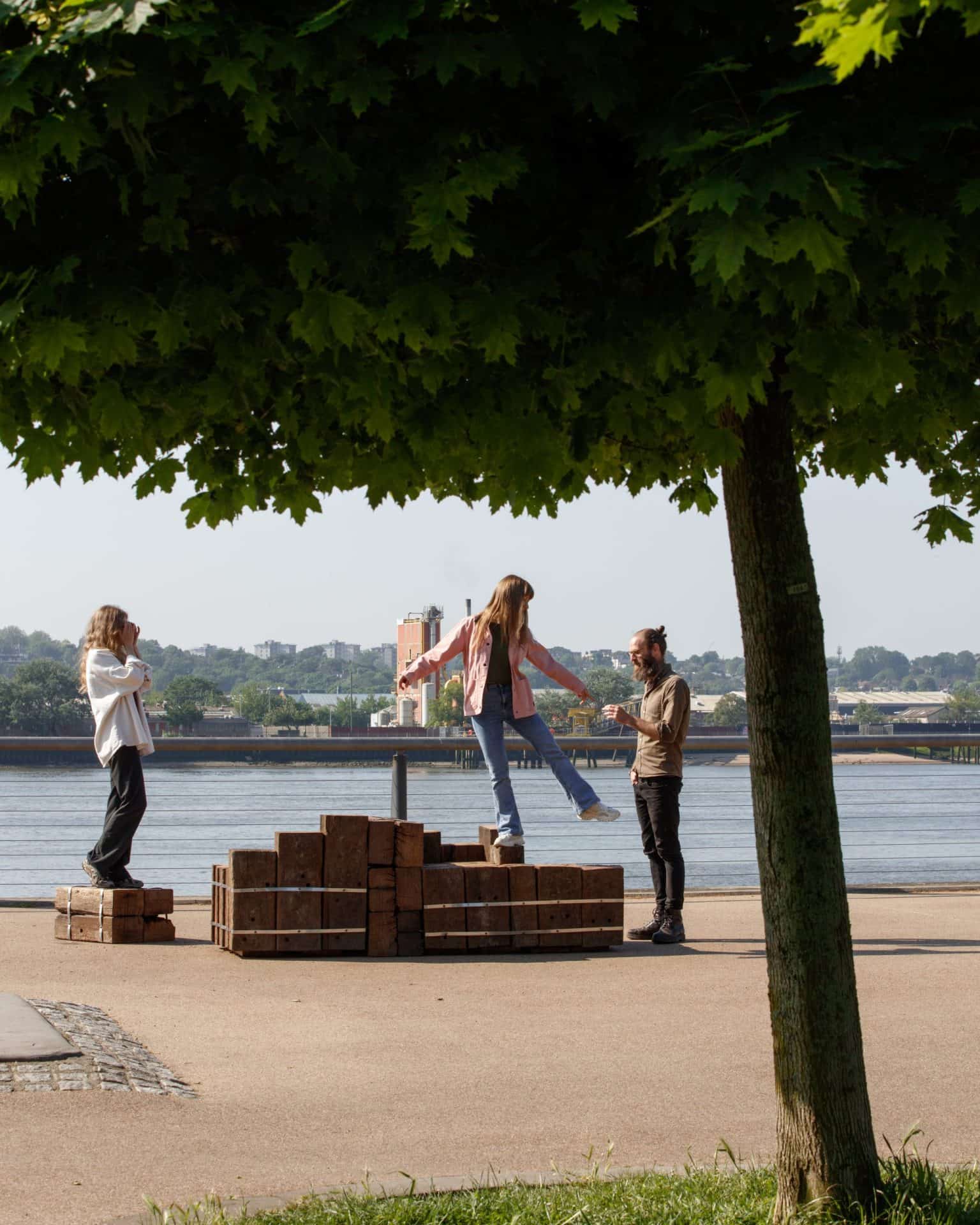 Three people standing on a bench in the Royal Docks