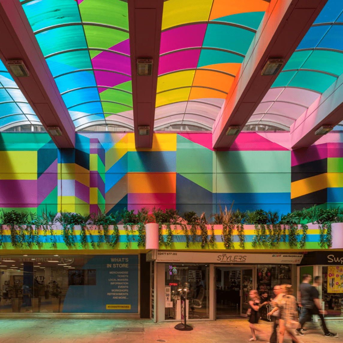 A colourful pattern on the ceiling and walls of a shopping centre interior