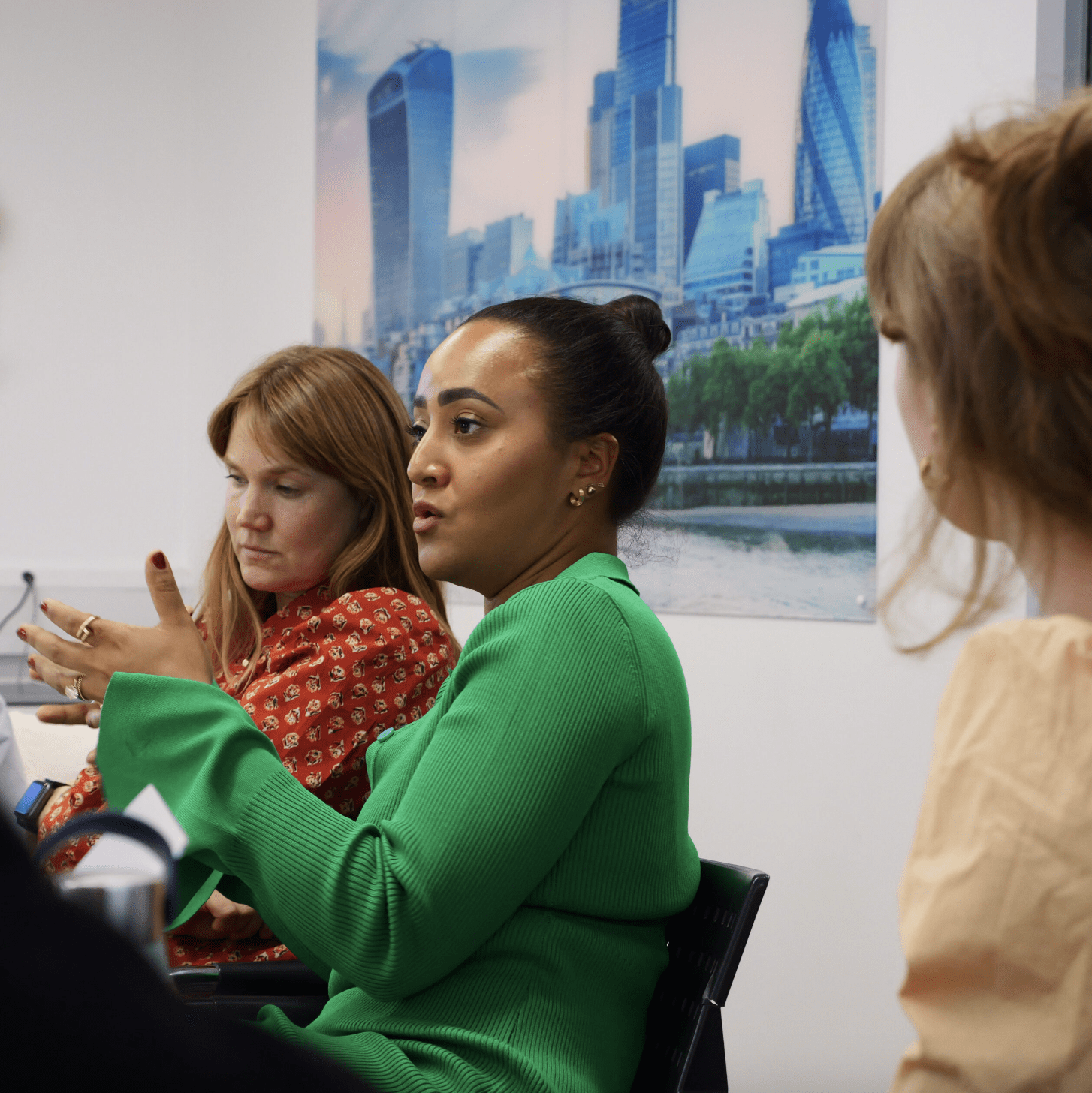 A woman in a green blouse gesturing in a meeting setting